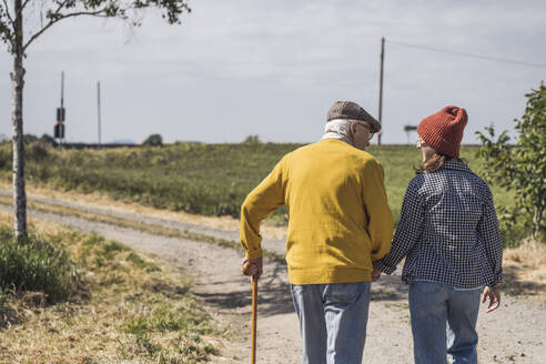 Senior man walking with granddaughter on road - UUF28941