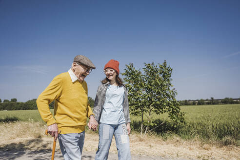 Happy senior man holding hands and walking with granddaughter - UUF28942