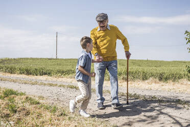 Cheerful senior man having fun with grandson on road - UUF28946