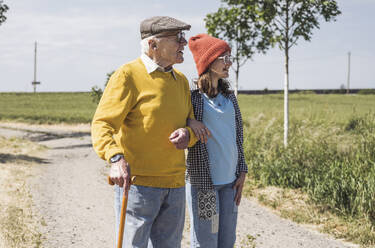 Smiling girl standing with grandfather at field - UUF28950