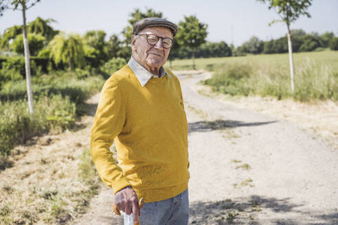 Lächelnder älterer Mann mit Baskenmütze auf der Straße stehend - UUF28953