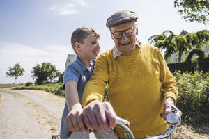 Happy grandfather with grandson sitting on bicycle - UUF28963