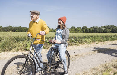 Happy grandfather with granddaughter sitting on bicycle - UUF28970