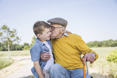 Großvater küsst Enkel auf die Wangen auf dem Feld - UUF28980