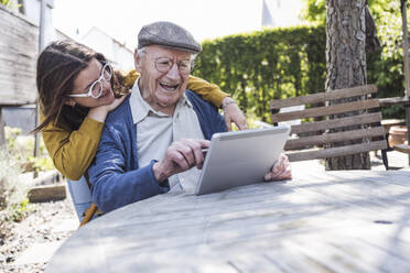 Mädchen mit Großvater benutzt Tablet-PC am Tisch - UUF29016