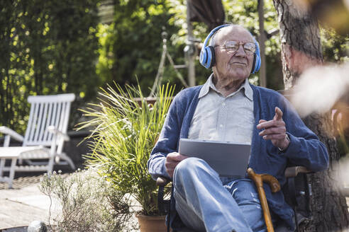 Senior man wearing wireless headphones listening to music - UUF29032