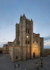 Exterior of aged historic Avila cathedral with brick walls and arched windows located on pavement against evening sky in Spain - ADSF44340