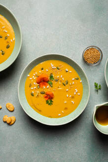 Top view of appetizing vegetarian pumpkin cream soup with herbs and sesame seeds served in bowls on table - ADSF44349