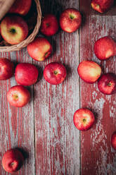 From above wicker basket filled with fresh ripe red apples placed on shabby timber cupboard during harvest season - ADSF44357