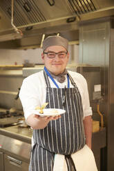 Portrait of smiling cook holding plate - ISF26088