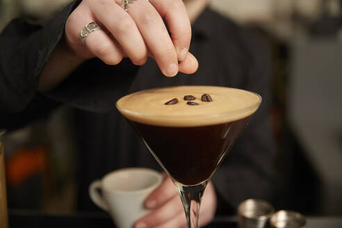 Bartender garnishing coffee cocktail with coffee beans - ISF26093