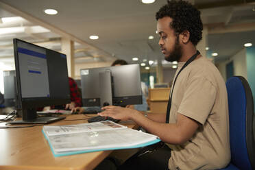 Male student using computer in library - ISF26109