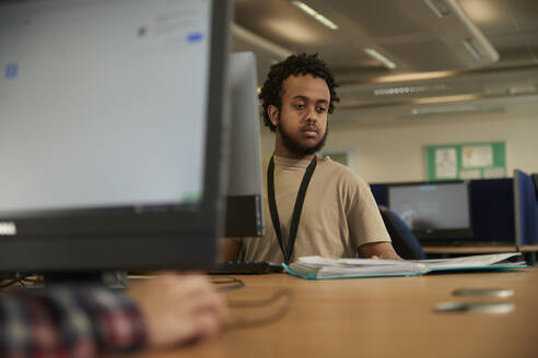 Male student using computer in library - ISF26111