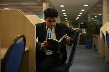 University student reading book homework in library - ISF26129