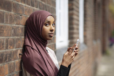 Portrait of young woman in hijab using phone - ISF26134