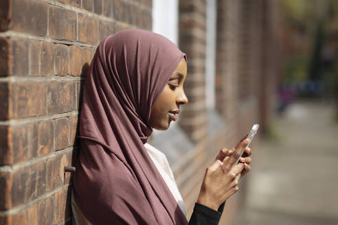 Young woman in hijab using phone - ISF26135