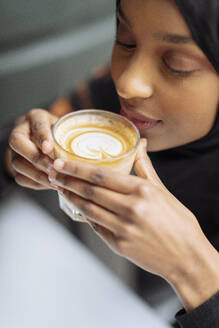 Young woman in hijab drinking coffee - ISF26136