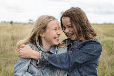 Smiling girl friends (10-11) hugging in field - ISF26158