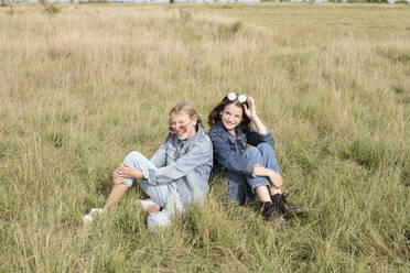 Portrait of smiling girl friends (10-11) sitting in field - ISF26166