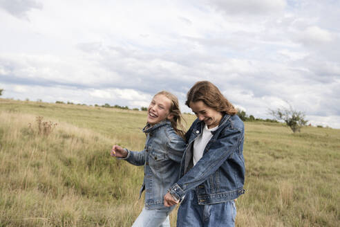 Smiling girl friends (10-11) frolicking in field - ISF26172