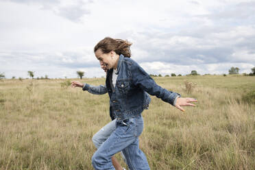 Smiling girl friends (10-11) frolicking in field - ISF26173