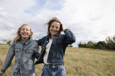 Smiling girl friends (10-11) frolicking in field - ISF26174