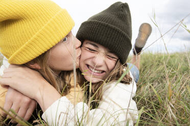 Smiling girl friends (10-11) lying in grass and kissing - ISF26202