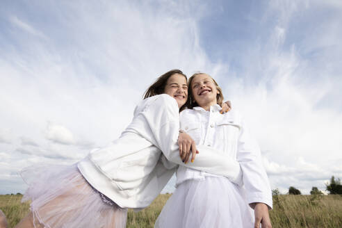 Smiling girl friends (10-11) hugging in field - ISF26229