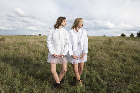 Smiling girl friends (10-11) doing ballet pose in field - ISF26231