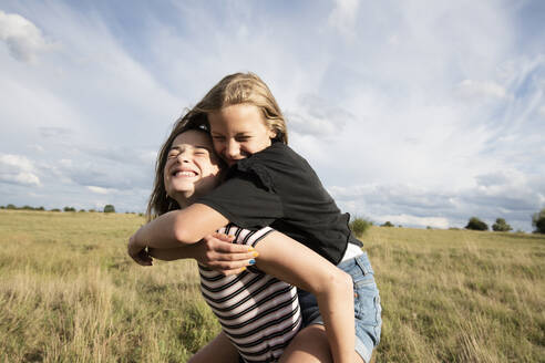 Smiling girl (10-11) giving friend piggyback ride - ISF26233