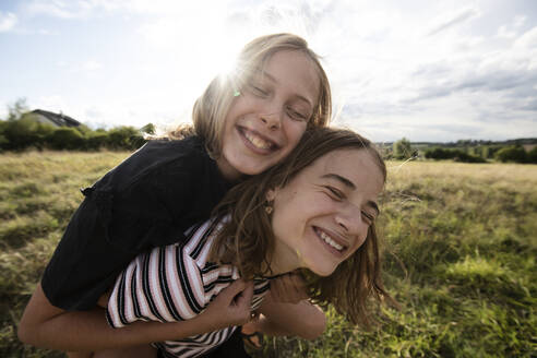 Smiling girl (10-11) giving friend piggyback ride - ISF26238