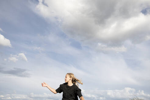 Blond girl (10-11) in black blouse against sky - ISF26239