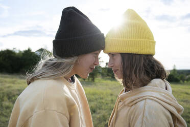 Smiling girl friends (10-11) wearing beanies in field - ISF26242