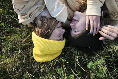 Smiling girl friends (10-11) lying in meadow - ISF26249