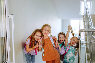 Happy schoolgirls standing at school staircase - MDOF01404