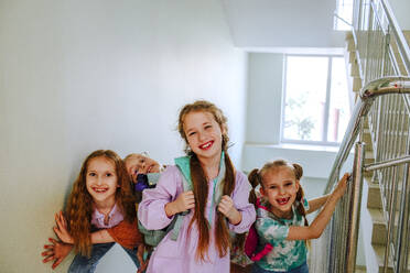 Happy schoolgirls standing on stairs at break time - MDOF01406