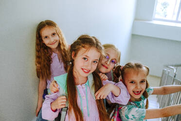 Smiling schoolgirls standing together on staircase - MDOF01407