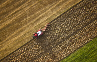 Farmer using tractor and plowing land at sunrise - CVF02442