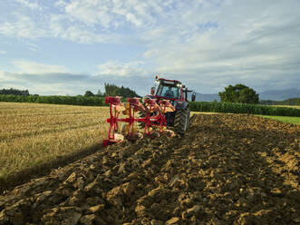 Landwirt pflügt Feld mit Traktor bei Sonnenaufgang - CVF02443