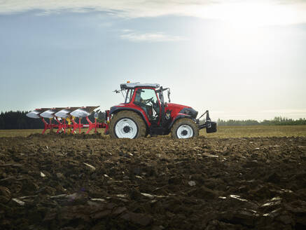 Landwirt pflügt Feld mit Traktor bei Sonnenaufgang - CVF02445