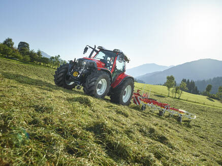 Landwirt mit Traktor und mäht Grasfeld in der Nähe des Berges - CVF02455