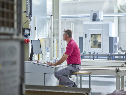 Engineer sitting and using computer in production factory - CVF02459