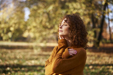 Young redhead woman with eyes closed at autumn park - ABIF02060
