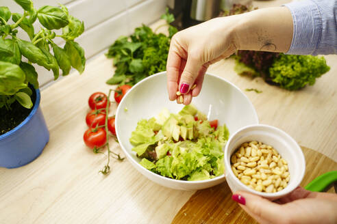 Hände einer Frau bei der Zubereitung von Gemüsesalat in einer Schüssel zu Hause - NJAF00419