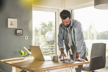 Geschäftsmann mit Smartphone am Schreibtisch im Home Office - UUF29068