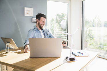 Happy freelancer using mobile phone at desk - UUF29079