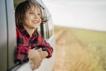 Lächelnder Junge schaut aus dem Autofenster - ANAF01555