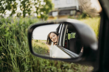 Spiegelung eines Jungen, der aus dem Autofenster in den Seitenspiegel schaut - ANAF01560