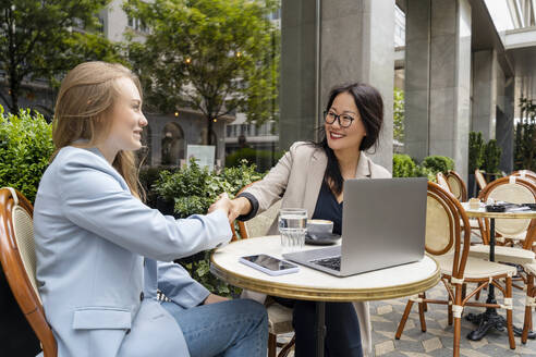 Business partners doing handshake at sidewalk cafe - NDEF00824