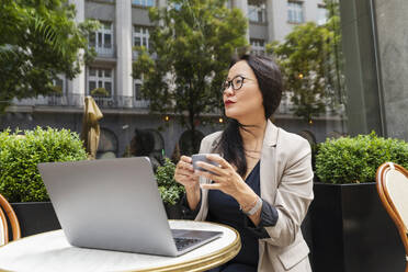 Geschäftsfrau mit Kaffee und Laptop in einem Straßencafé - NDEF00829